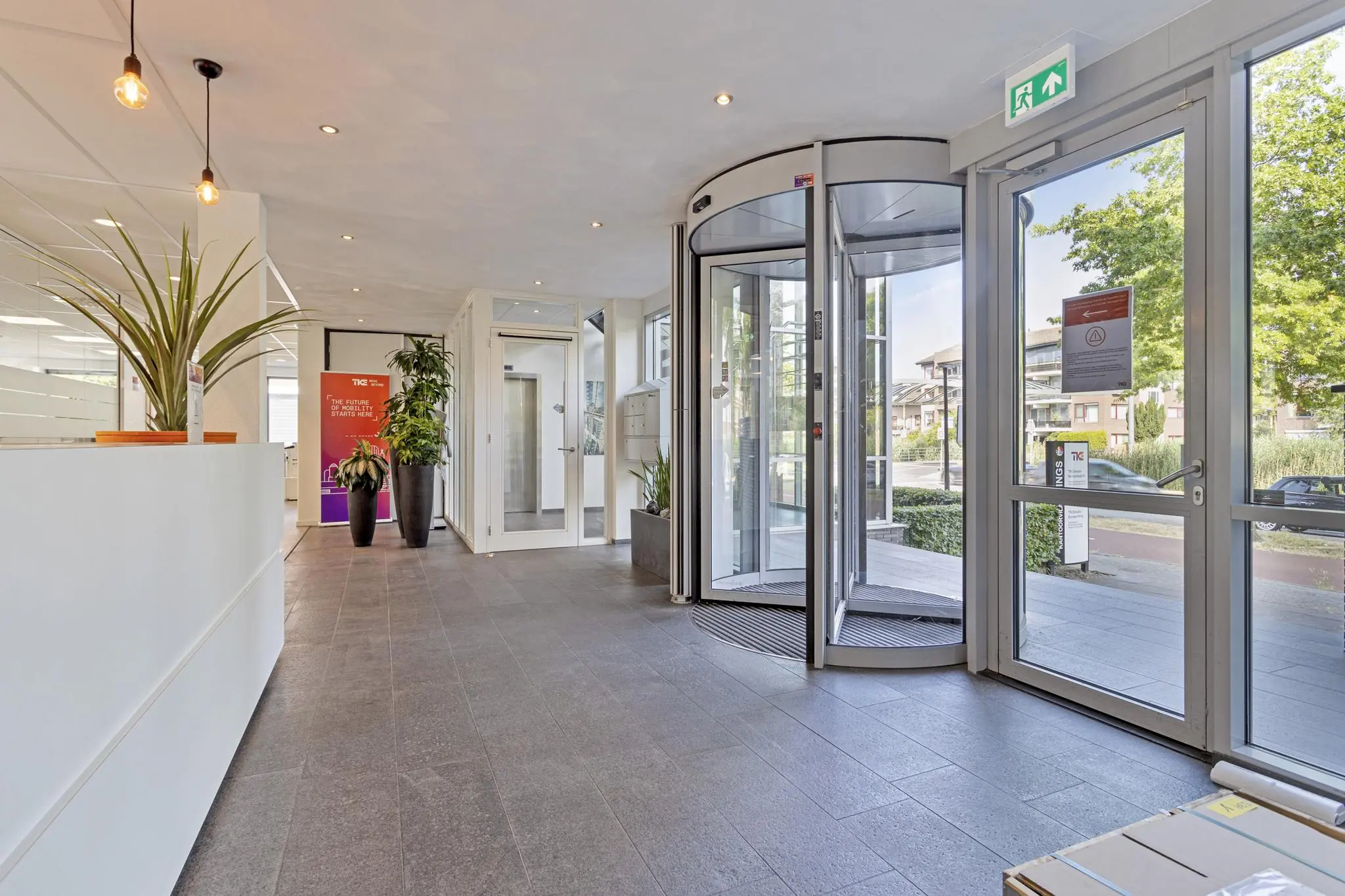 Moderne entreehal van een kantoorpand aan de Fascinatio Boulevard met draaideur, planten en strakke inrichting.